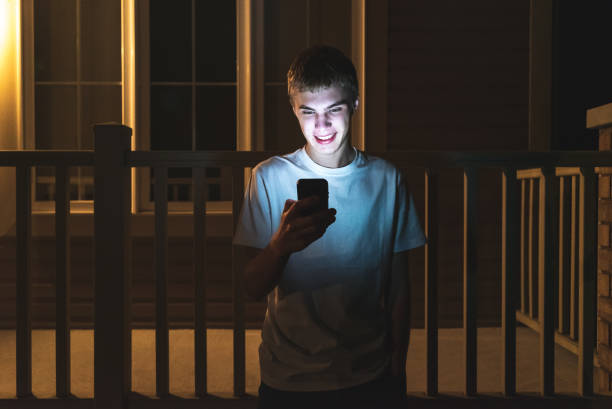 Happy teenager on mobile phone at night. stock photo