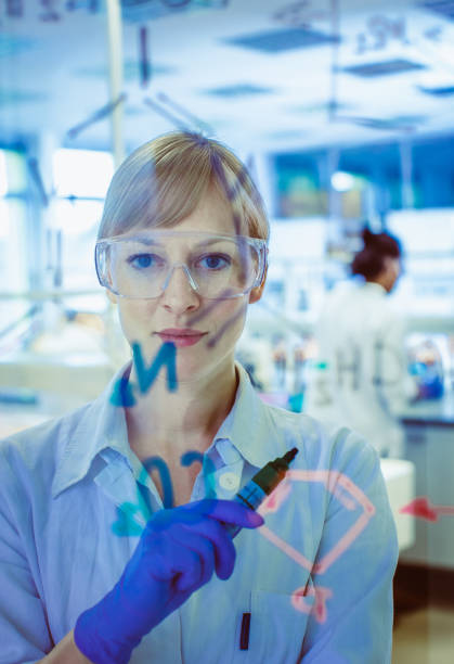 istock Female Scientist Writing a Chemical Formula on Glass 1062501748