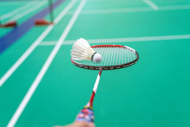 istock hand holding badminton shuttlecock with racket on court. 1062502298