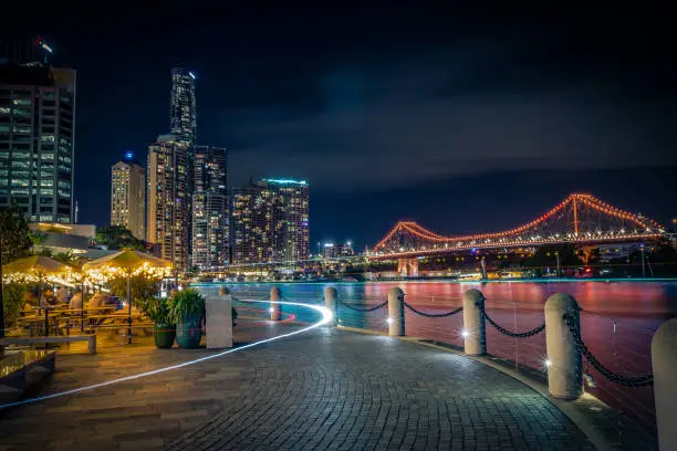 Perspective view of paved seafront with bright lights of long exposure in night time, Brisbane