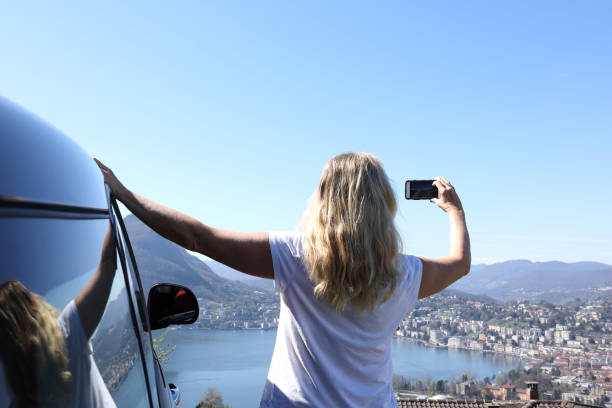 istock Woman leans against car while taking photo 1062511192