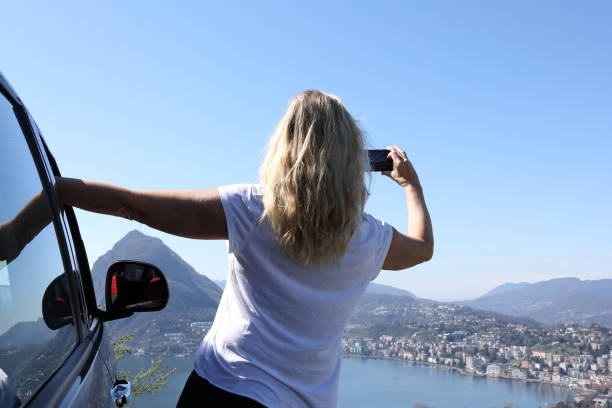 istock Woman leans against car while taking photo 1062512894