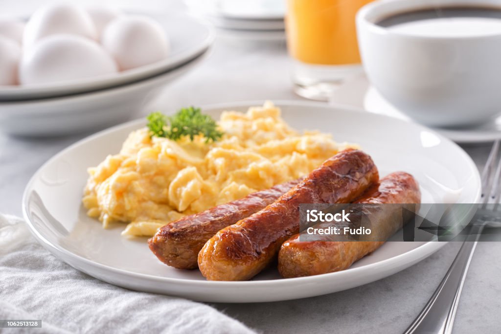 Scrambled Eggs and Breakfast Sausage A plate of delicious scrambled eggs and breakfast sausage with coffee and orange juice. Breakfast Stock Photo