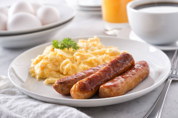 Scrambled Eggs and Breakfast Sausage A plate of delicious scrambled eggs and breakfast sausage with coffee and orange juice. breakfast stock pictures, royalty-free photos & images