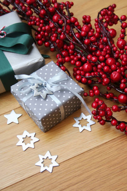 istock Christmas silver gift boxes on wooden table with red berries 1062518180