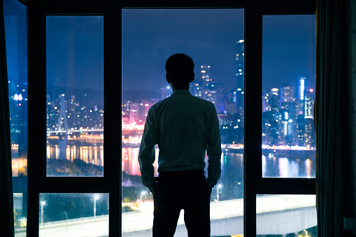 Businessman standing by window at night