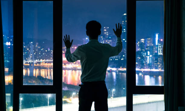 istock Businessman standing by window at night,Hand touching window 1062519594