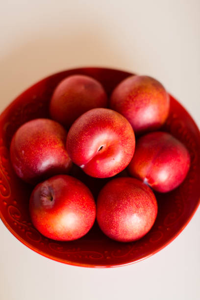 istock Red Plums in a Red Bowl 1062524392