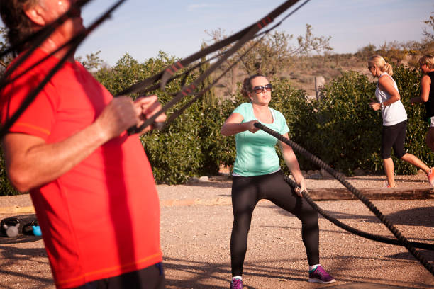 Sunshine Boot Camp A mixed group of people exercising in the sun - battle ropes, suspension training and circuit training circuit training stock pictures, royalty-free photos & images