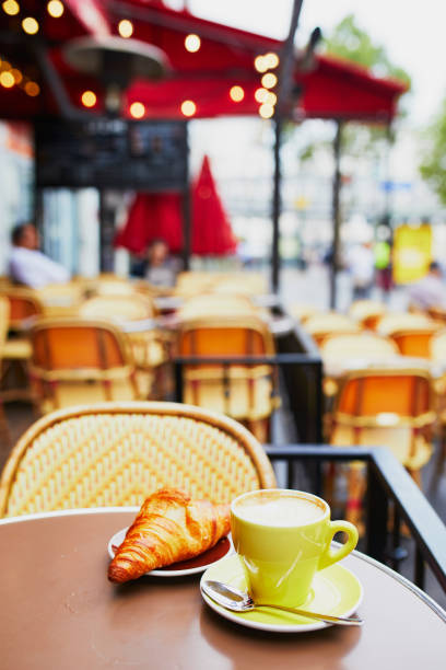 Cup of fresh hot coffee and traditional French croissant on table of Parisian outdoor cafe in Paris, France
