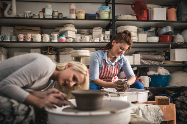 istock Two young ladies making pottery on a pottery wheel in the art studio 1062542450
