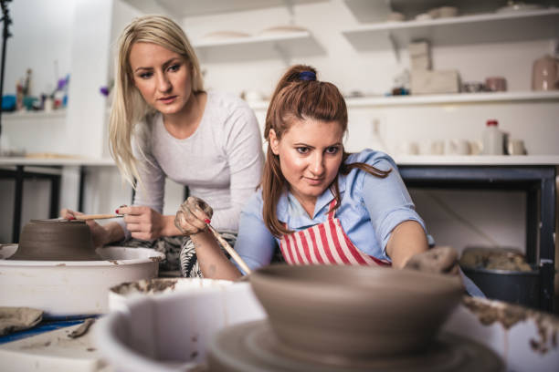 istock Two young ladies making pottery on a pottery wheel in the art studio 1062542494