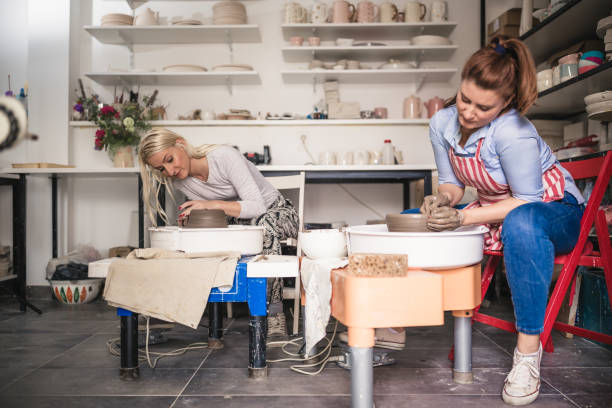 istock Two young ladies making pottery on a pottery wheel in the art studio 1062542598