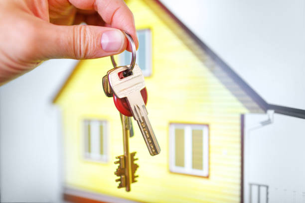 House keys in the hands against the background of the finished built yellow building - fotografia de stock