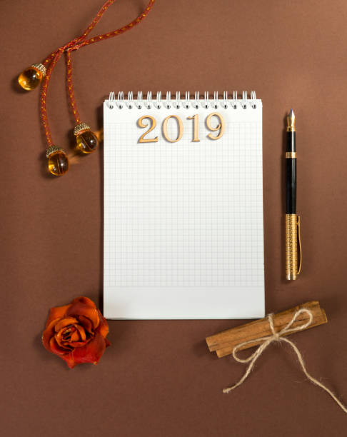 istock clean Notepad sheet, fountain pen, writing space, Christmas ball, artificial transparent icicle, cinnamon sticks on brown background, top view, lettering 2019, flat lay 1062549248