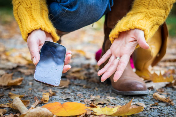 istock Woman picking damaged mobile phone from the ground. 1062552240