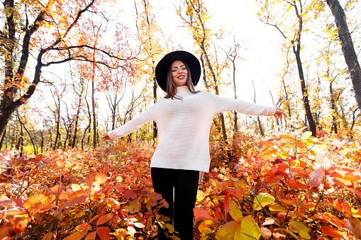 beautiful happy woman having fun in park on autumn sunny day. wide angle