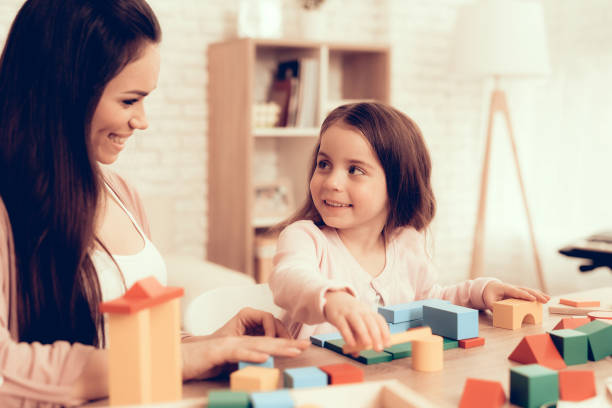 istock Smiling Mom and Daughter Playing Cubes on Table. 1062557482