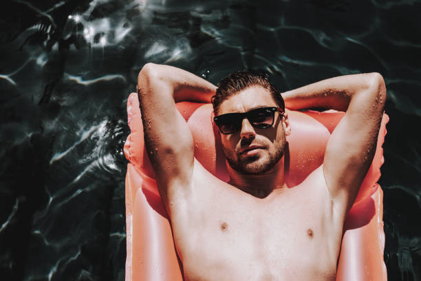 istock Young Handsome Man in Sunglasses on Air Mattress 1062558278