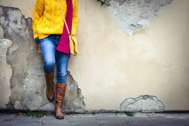 donna che indossa jeans, maglione in maglia gialla, sciarpa di lana, borsa e stivale in pelle. - single lane road foto e immagini stock