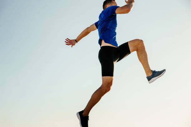 istock male athlete jumping on blue sky background. freedom concept 1062560208