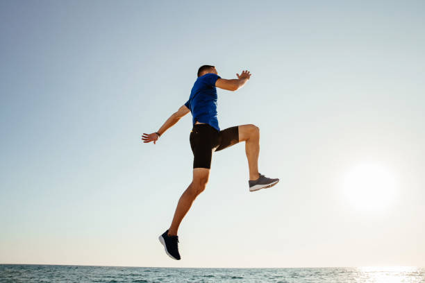 istock man jump up and flying in sunlight over sea 1062560246