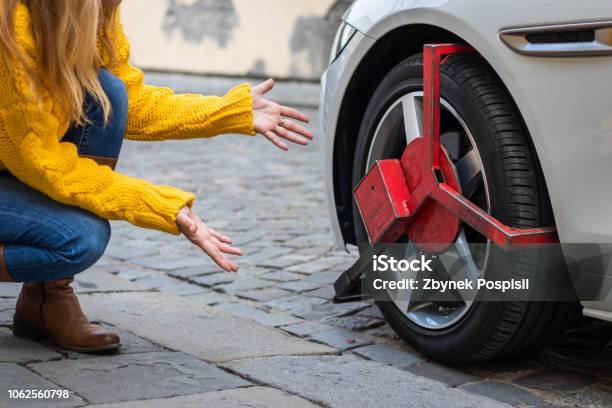 Verärgert Frau Schaut Ihr Geparktes Auto Mit Radklemme Stockfoto