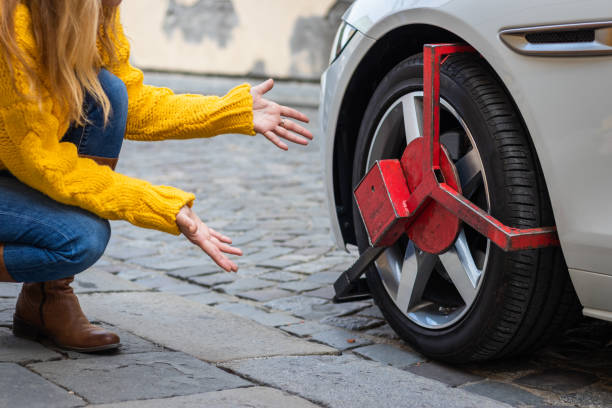 Upset woman looks at her parked car with wheel clamp. Punishment for illegal parking at street. car boot stock pictures, royalty-free photos & images