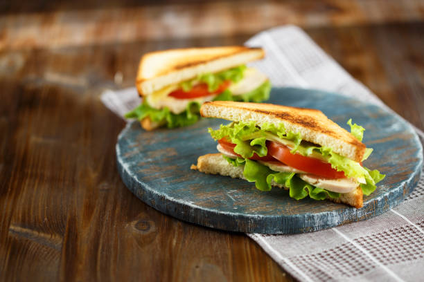 istock Appetizing sandwich with chicken, tomatoes, lettuce, cheese on a wooden plate on a dark background 1062563982