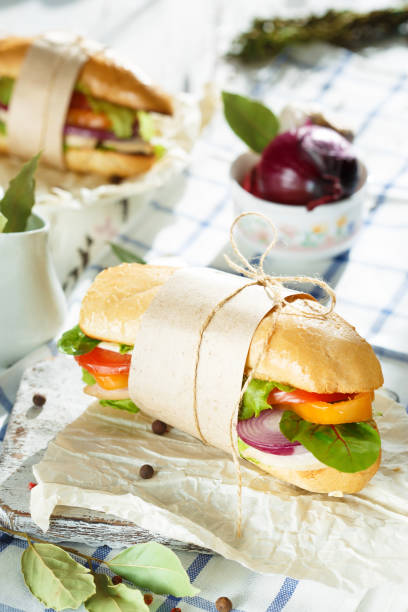 istock Dining table. Appetizing sandwich from crispy bread with chicken, tomatoes, onion, lettuce, cheese and spices on a light wooden background. 1062564178