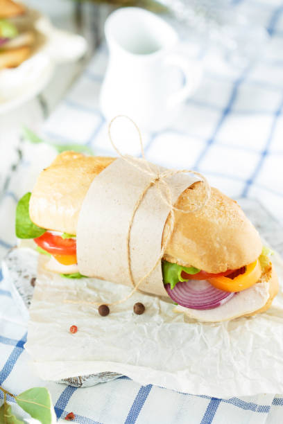 istock Dining table. Appetizing sandwich from crispy bread with chicken, tomatoes, onion, lettuce, cheese and spices on a light wooden background. 1062564192