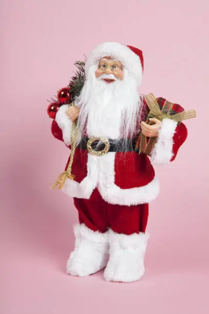 a santa claus figurine plush on a pink background. Color harmony. Minimal still life color photography