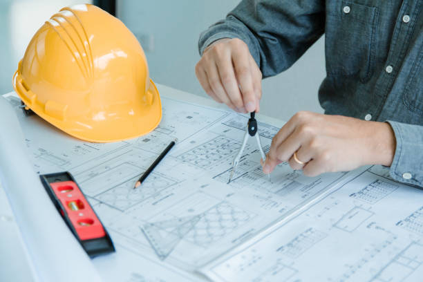 istock Concept architects,engineer holding Circus pointing equipment architects On the desk with a blueprint in the office Vintage Sunset light.Selective Focus 1062566814