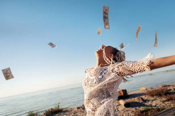 Photo of Successful prosperous freelancer throwing her money in the air