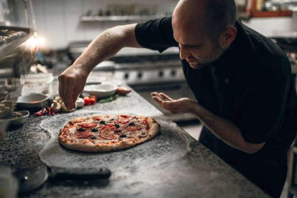 Putting seasoning on pizza The main chef putting final ingredients on italian pizza in the restaurant pizzeria stock pictures, royalty-free photos & images