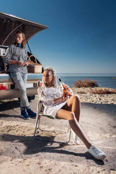istock Smiling woman chilling while drinking beer near mobile home with her man 1062576716