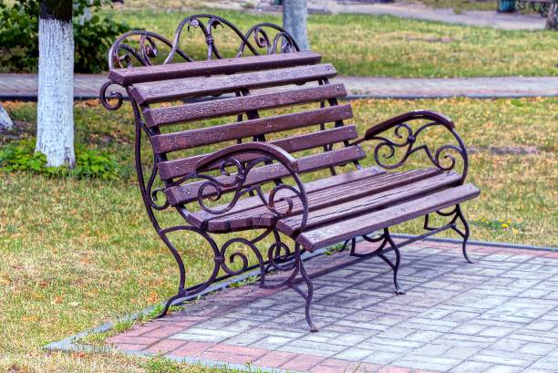 istock a brown bench stands on the sidewalk in green grass 1062578758
