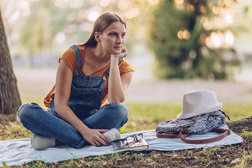 One woman, beautiful young woman sitting on a meadow in nature alone.