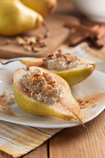 istock Half pears with cottage cheese, nuts and cinnamon on white dish. 1062593738