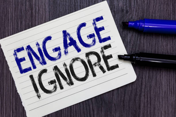 istock Writing note showing Engage Ignore. Business photo showcasing Silent Treatment Manipulative Punishment Sulking Shunning Notebook Paper Reminder Communicating ideas Markers Wooden background. 1062607036