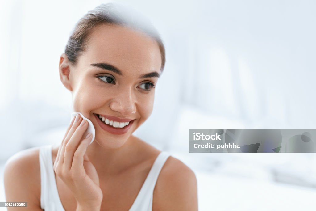 Makeup Remove. Girl Cleaning Face Skin With Cosmetic Pad Makeup Remove. Beautiful Girl Cleaning Face Skin With White Cosmetic Pad. High Resolution Facial Cleanser Stock Photo