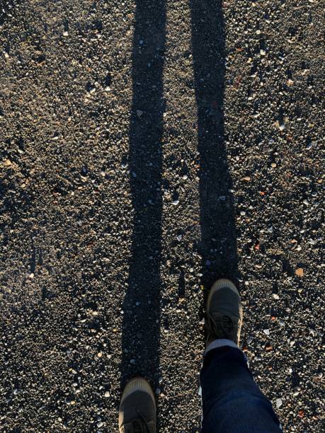 istock Shadows of two legs on the road 1062664704