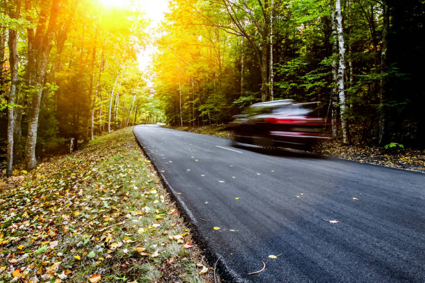 istock Car driving thru autumn road with sunbeams 1062672772
