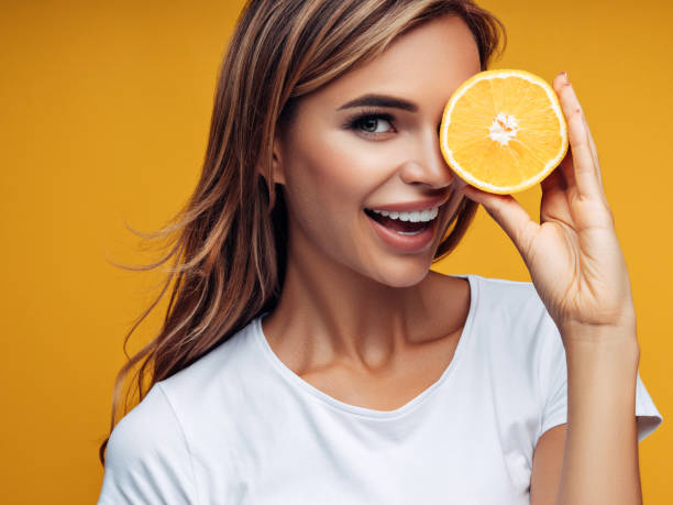 Beautiful girl showing two halves of lemon Beautiful girl showing two halves of lemon vitamin c stock pictures, royalty-free photos & images