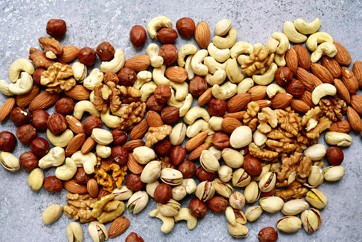 Assortment of nuts on  a light slate or stone background - healthy snack.Top view with copy space.