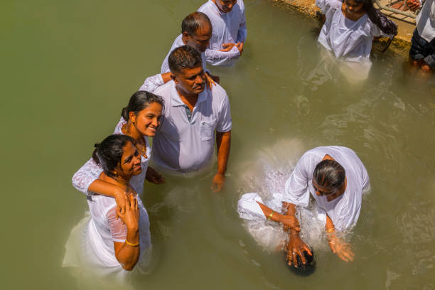 pilgrims baptizing in the jordan river, in the yardenit baptismal site. northern israel. - batismo imagens e fotografias de stock