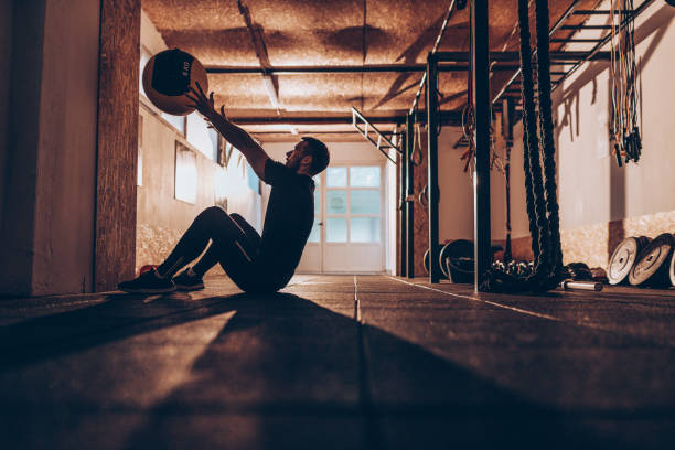 cara muscular na cruz training - jogando a bola para os músculos abdominais - weight training body building men human muscle - fotografias e filmes do acervo