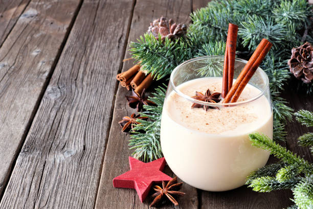 istock Glass of Christmas eggnog with tree branches and decorations on wood 1062698596