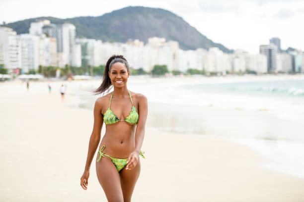 istock Young woman walking by water's edge in bikini, Copacabana Beach 1062698606