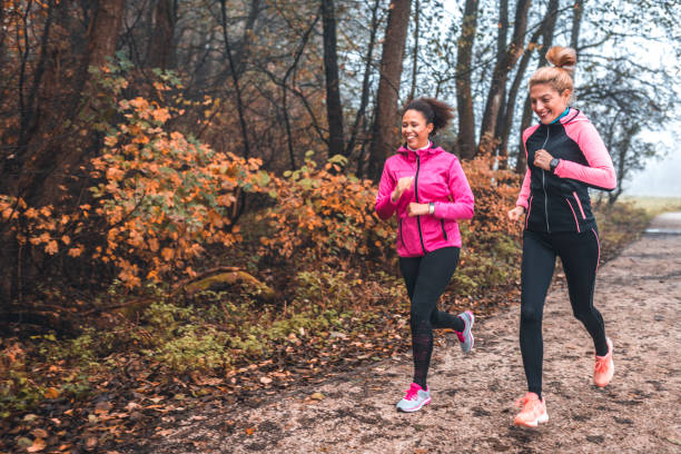 giovani sportive che corrono nella natura la mattina nebbiosa - jogging autumn young women women foto e immagini stock